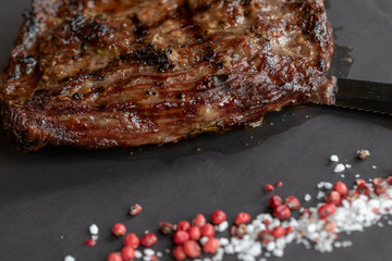 Cut grilled steak with pink pepper, close-up