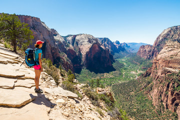 Naklejka premium Young woman is looking at the magnificent view from Angel's landing in Zion National park. Travel and adventure concept.