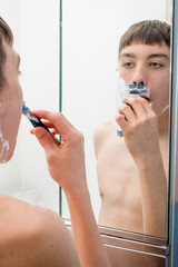 Teenage boy shaving in the morning