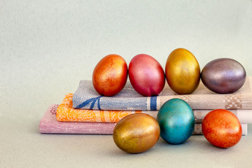 seven bright multi-colored Easter eggs lying in a row on linen napkins