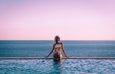 girl in a swimsuit near the panoramic pool on the background of the sea relaxes
