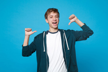 Portrait of attractive young man in casual clothes pointing thumbs on himself isolated on blue background in studio. People sincere emotions, lifestyle concept. Mock up copy space. Advertising area.