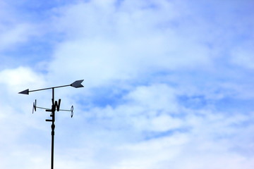 Weathervane against a blue cloudy sky