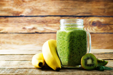 Spinach banana kiwi smoothie on a dark wood background