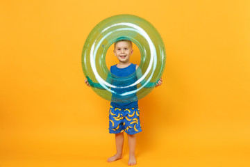 Kid boy 3-4 years old in blue beach summer clothes hold inflatable ring isolated on bright yellow orange wall background children studio portrait. People childhood lifestyle concept Mock up copy space