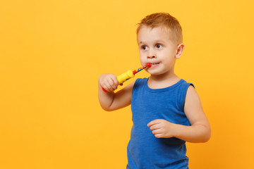 Kid boy 3-4 years old in blue shirt brush his teeth with toothbrush isolated on bright yellow orange wall background, children studio portrait. People, childhood lifestyle concept. Mock up copy space.