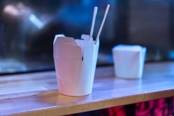 Close up of white cardboard boxes of asian food with chopsticks.