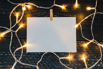 notepad on wooden desk with copyspace to add you text surrounded by fairy lights