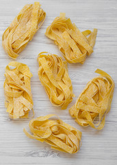 Uncooked pasta pappardelle on a white wooden background, top view. Overhead, flat lay. Close-up.