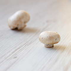 Raw champignon mushrooms on a white wooden surface, side view. Close-up.