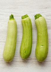 Fresh vegetable marrow zucchini on white wooden table, top view. From above, overhead. Close-up.