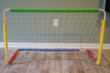 Portable mini indoor soccer net in a home basement