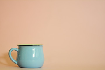 Photograph in flat style - a blue cup on a peach background and a place for text.
