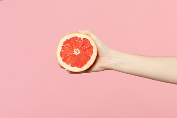 Close up cropped photo of female hold in hand fresh ripe half grapefruit fruit isolated on pink pastel wall background. Copy space advertising mock up. People vivid lifestyle, relax vacation concept. - Powered by Adobe
