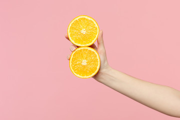 Close up cropped photo of female hold in hand two fresh ripe halfs orange fruit isolated on pink pastel wall background. Copy space advertising mock up. People vivid lifestyle, relax vacation concept.