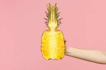 Close up cropped photo of female hold in hand fresh ripe half pineapple fruit isolated on pink...