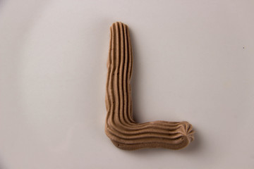 Sweet chocolate letter L drawn with whipped cream on a white plate
