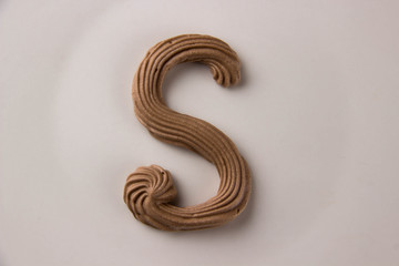 Sweet chocolate letter S drawn with whipped cream on a white plate - 253852721