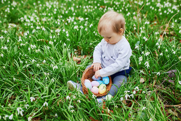 Cute little one year old girl playing egg hunt on Easter