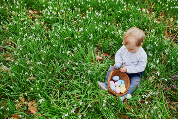 Cute little one year old girl playing egg hunt on Easter