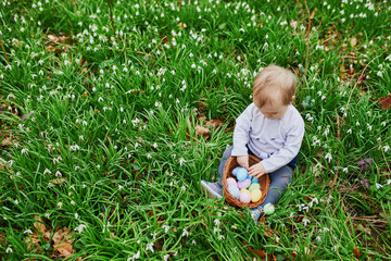 Cute little one year old girl playing egg hunt on Easter