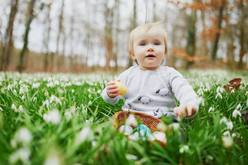Cute little one year old girl playing egg hunt on Easter