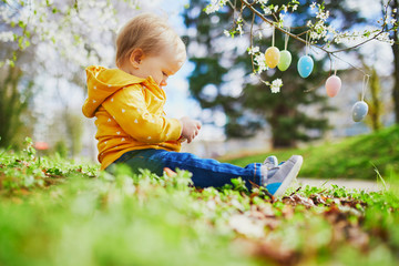 Cute little one year old girl playing egg hunt on Easter