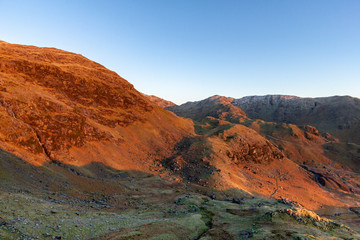 A view of a brown mountain slope with some partial snow and a majestic blue sky