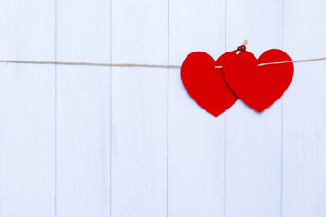 Two hearts hanging on a rope on woden background