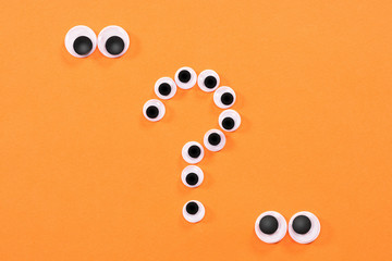 Googly eyes. Two strange persons with mad eyes look at some crazy toy eyes on orange background in...