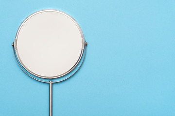 Top view image of circle hand mirror on blue background.