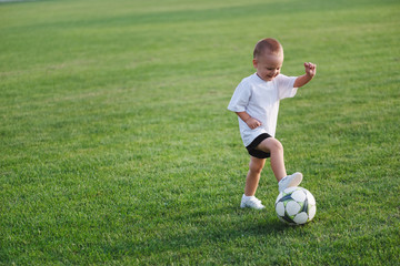 little happy boy on football field