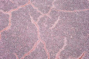 Purple asphalt pavement texture background with cracks, close up with small stones for design.