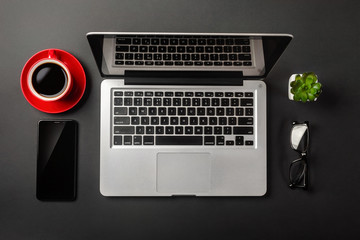 Elegant black office desktop with laptop and cup of coffee. Top view