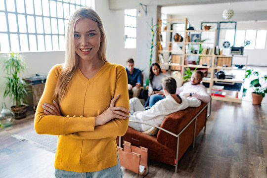 Portrait of smiling young businesswoman with coworkers in background in loft office