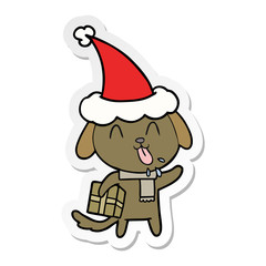 cute sticker cartoon of a dog with christmas present wearing santa hat