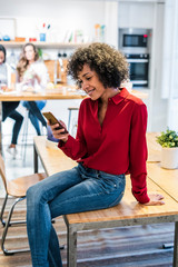 Smiling woman with cell phone sitting on table