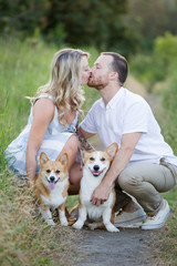 Couple kissing with corgi puppy and dog