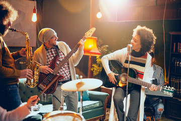 Band practice in home studio. Woman singing while rest of the band playing instruments.