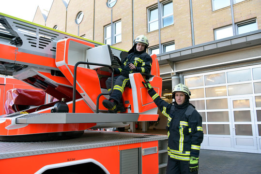 Portrait of two firefighters exercising at fire engine