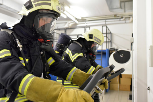 Two Firefighters With Respirator And Air Tank Exercising On Treadmill