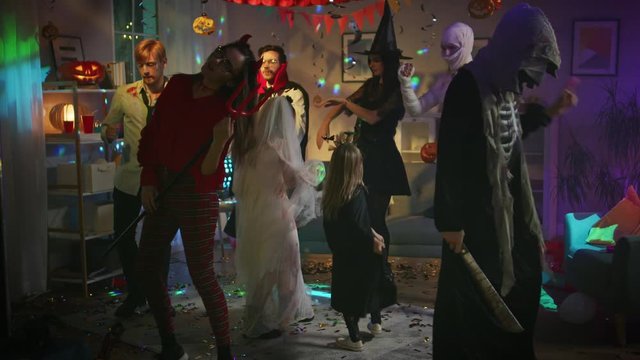 Halloween Costume Party: Group of Monsters Dancing in Decorated Room with Disco Ball Lights. Zombie, Vampire, Mummy, Beautiful Witch, She Devil, Death, Little Bloody Bride and Bat. In Slow Motion