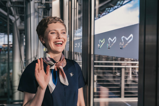 Happy airline employee waving out of the window at the airport