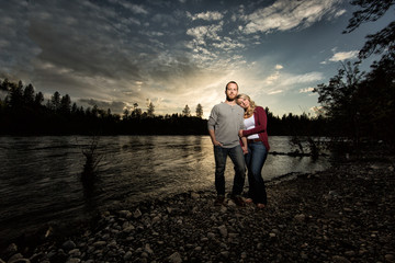Young attractive couple standing on beach in front of sunset