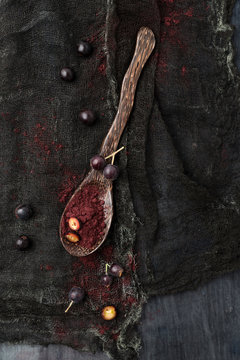 Spoon of Aronia powder and chokeberries on black cloth