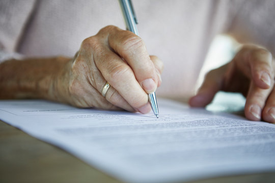 Senior woman's hand signing a document, close-up