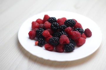 Berries on the white plate on light background