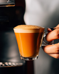 Vaso pequeño de café agarrado con mano de mujer