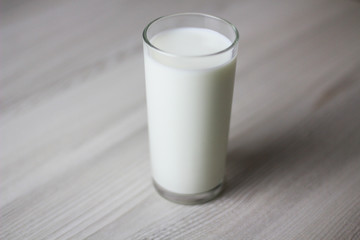 Glass with milk on the light wooden table