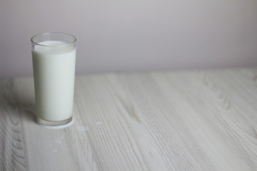 Glass with milk on the light wooden table